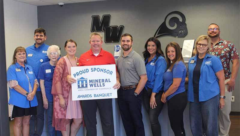 Mineral Wells office and Mineral wells Chamber of Commerce holding a sign in being a proud sponsor for the annual banquet. 